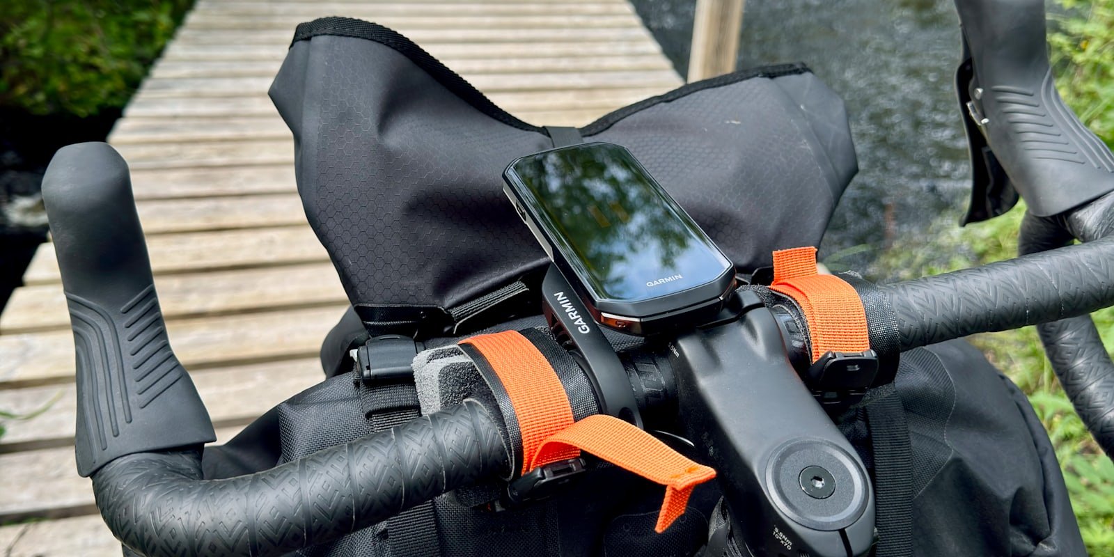 Guidon de vélo équipé d'un compteur GPS et d'une sacoche, sur une passerelle en bois