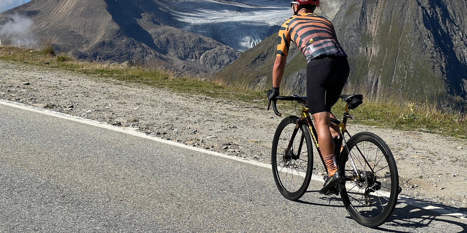 Cycliste sur une route de montagne en plein soleil, glaciers en arrière-plan