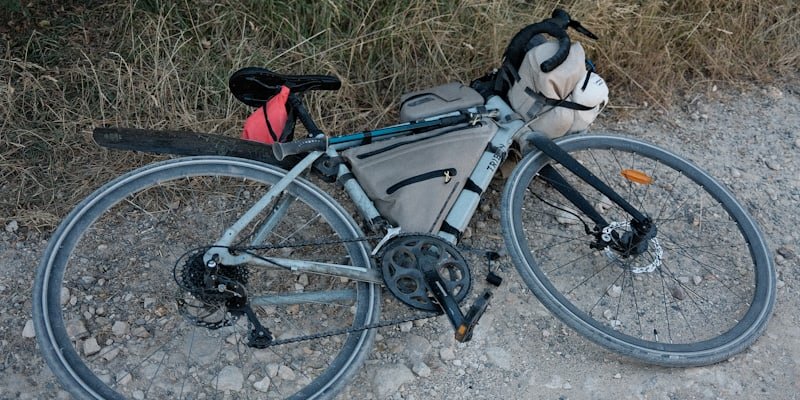 Vélo de gravel chargé de sacoches, posé au bord d'un chemin caillouteux